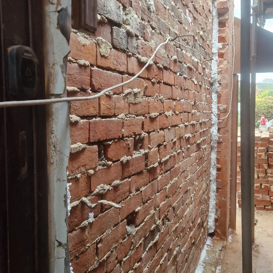 New brick wall with fresh mortar joints along a side return