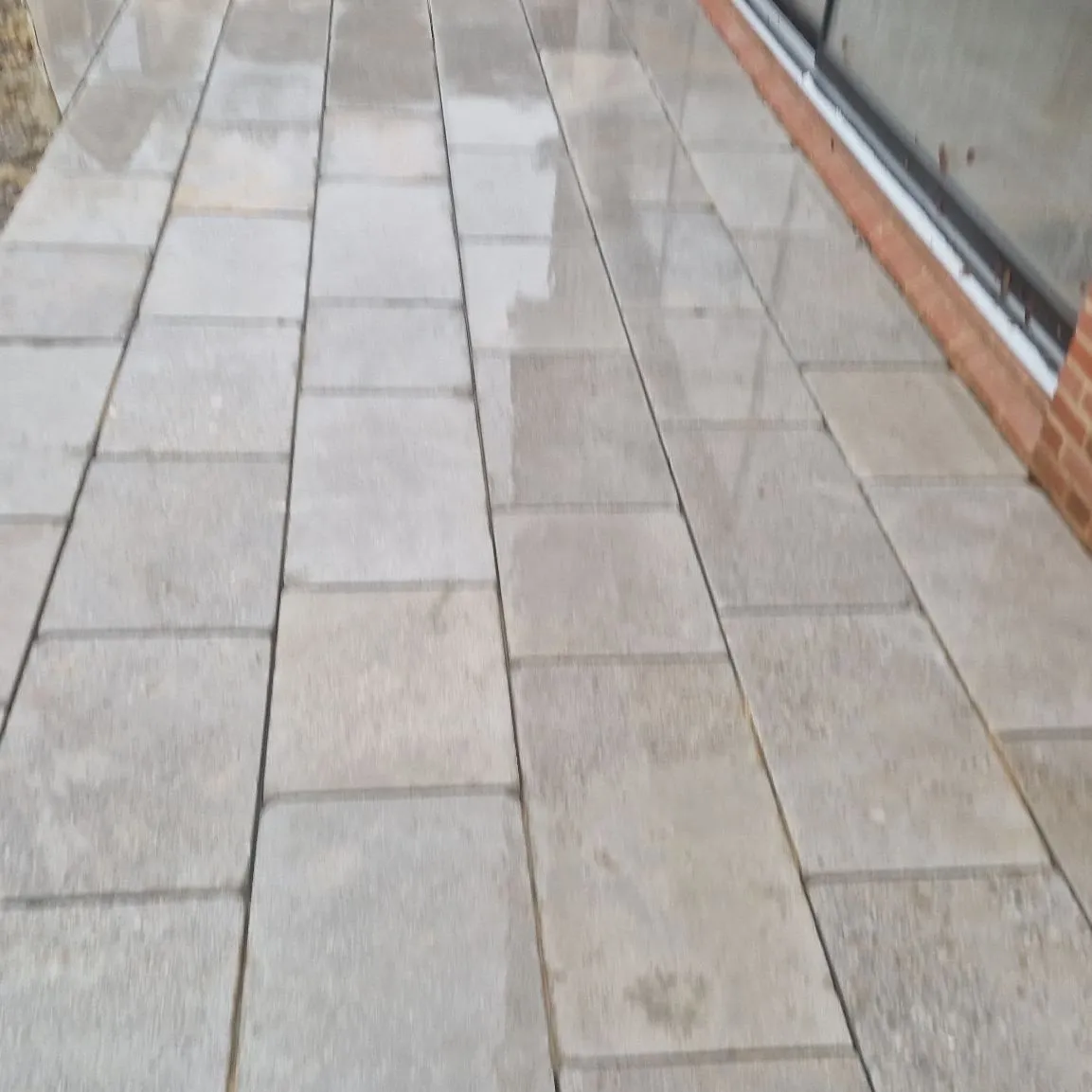 Large-format grey paving slabs laid tight along the back of a house