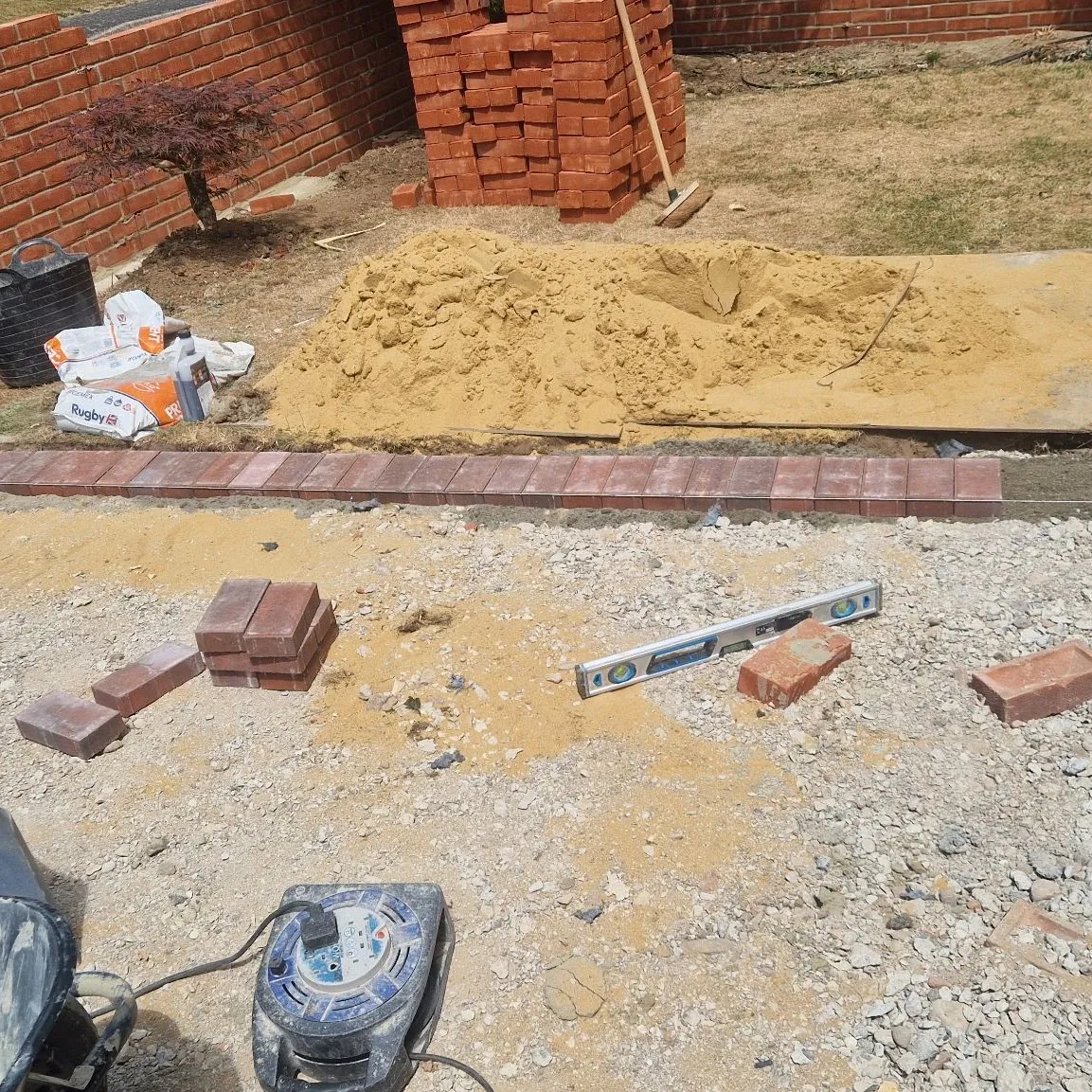 Sharp sand bed and block paving edging being set out with a spirit level