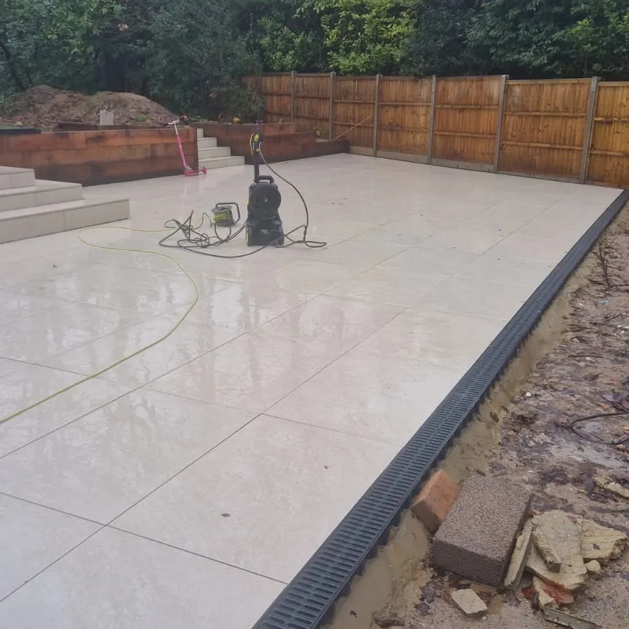 Pale porcelain patio laid with a drainage channel along the edge