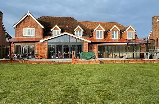 Large brick house with a wide glazed rear extension opening onto the lawn