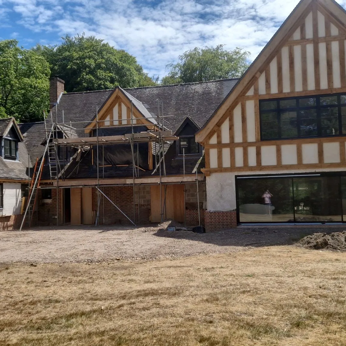 Tudor-style house under renovation with scaffolding and large new glazing